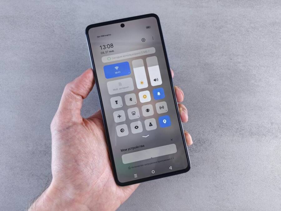 Close-up of a hand holding a smartphone with settings panel visible, focus on screen.