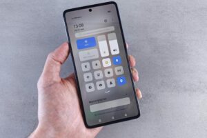 Close-up of a hand holding a smartphone with settings panel visible, focus on screen.