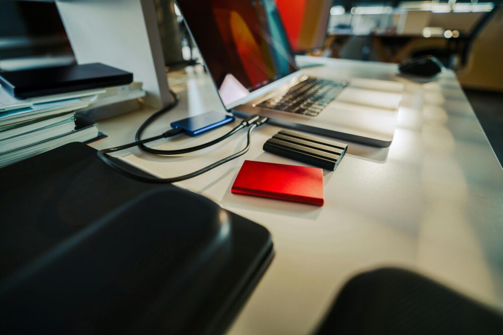 A neatly organized office desk featuring a laptop and several external hard drives, perfect for a digital workspace.