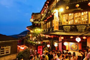 Vibrant evening view of Jiufen Old Street with lanterns and crowds in New Taipei City.