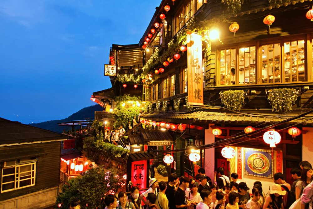 Vibrant evening view of Jiufen Old Street with lanterns and crowds in New Taipei City.