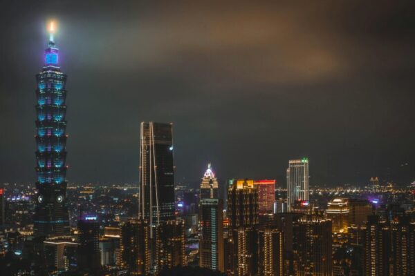 Night cityscape featuring the illuminated Taipei 101 tower and surrounding skyline in Taipei, Taiwan.
