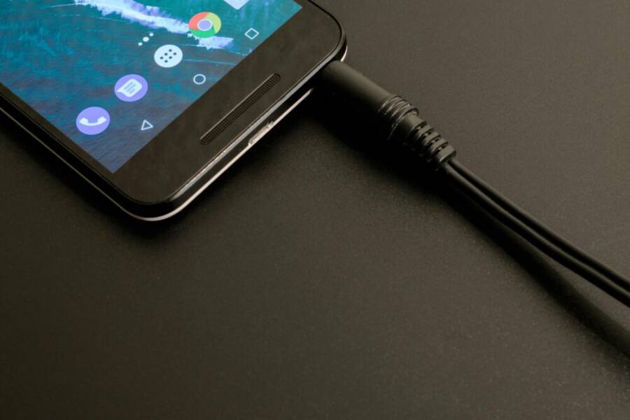 Close-up of a smartphone being charged, displaying a modern interface on a dark backdrop