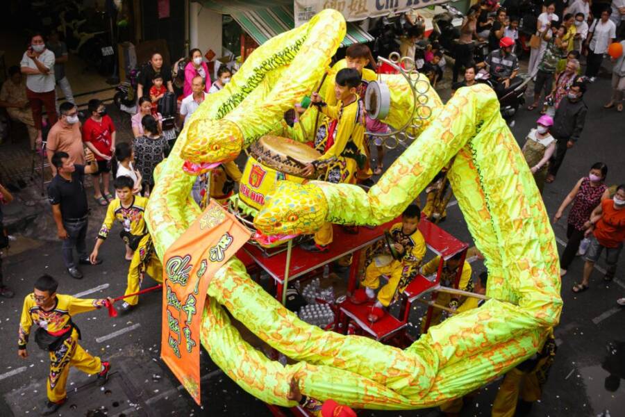 Colorful street parade in Ho Chi Minh City celebrating Vietnamese New Year 2025 with a giant snake mascot.