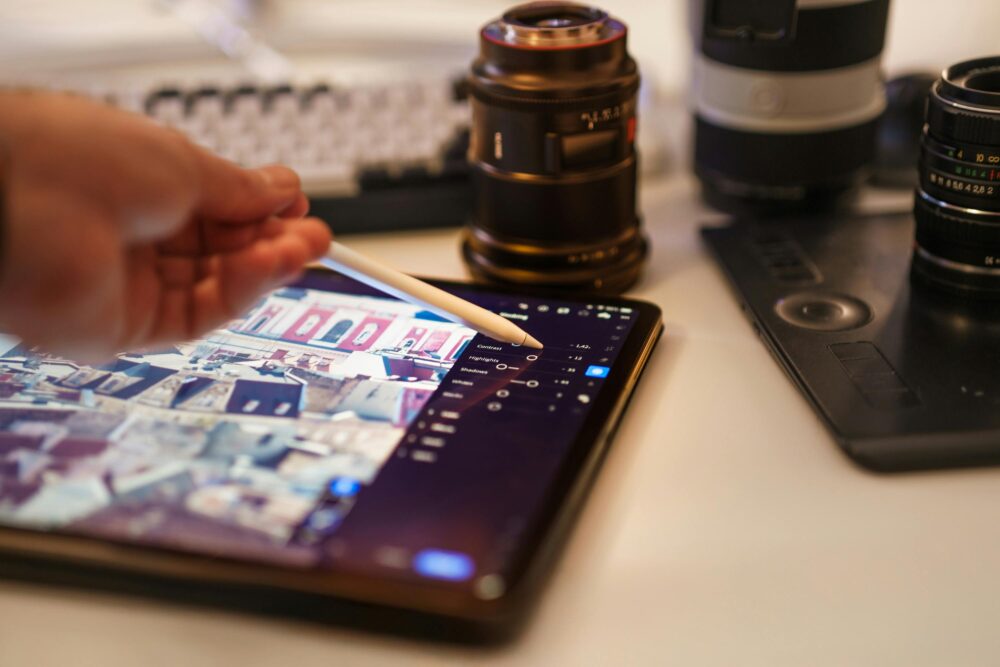 A detailed view of a professional photography editing setup with tablet and lenses
