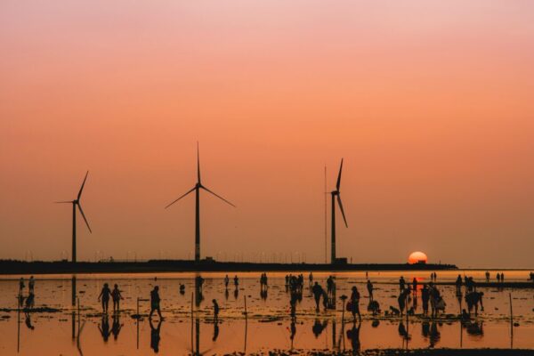 Breathtaking sunset at Taichung Gaomei Wetlands with wind turbines and silhouetted people.