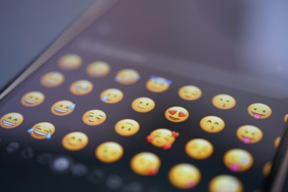 A close-up view of various emojis on a smartphone screen, symbolizing digital communication and social media use.