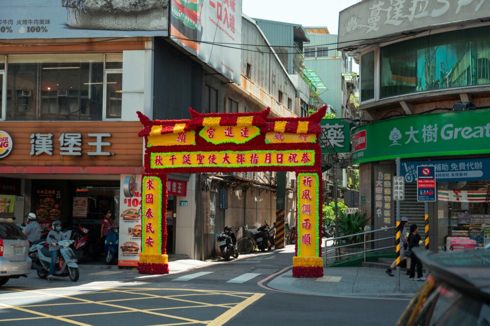 A vibrant traditional archway with colorful decorations on a bustling Taipei street