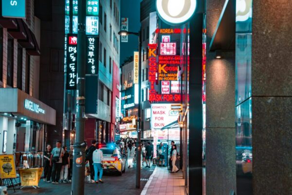 A bustling night scene in Myeongdong, Seoul, showcasing vibrant signs and street activity.