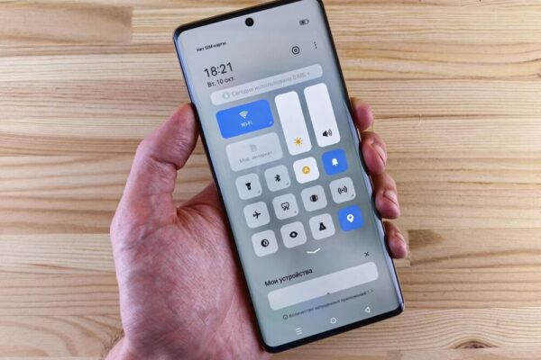 A hand holding a smartphone displaying the control center against a wooden backdrop