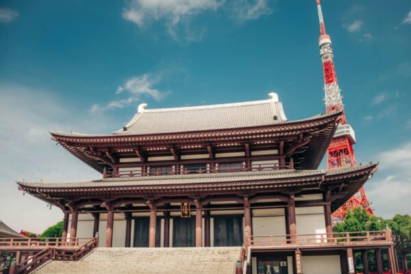 Beautiful summer view of Tokyo Tower behind the historic Zojoji Temple under a clear blue sky.