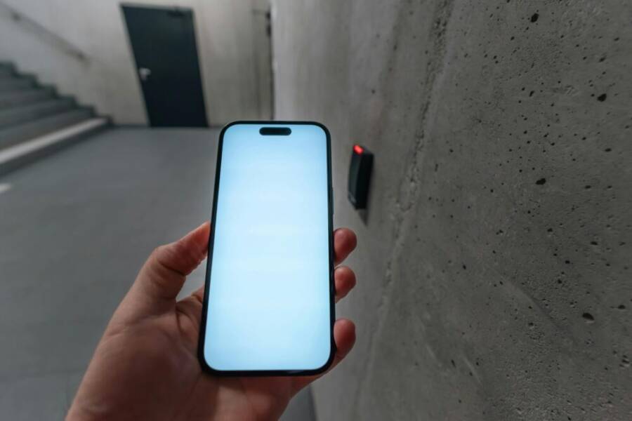 A smartphone unlocking a secure door using NFC technology in a modern building stairwell