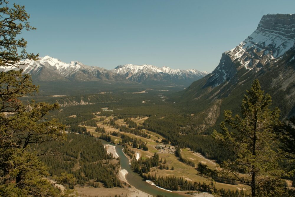Panoramic view of Bow Valley flanked by majestic mountains in Banff National Park during spring.
