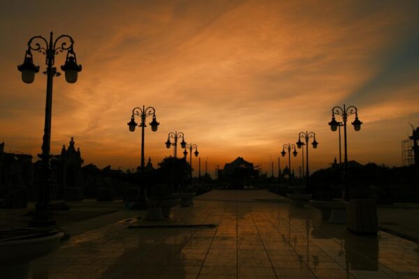 Dramatic sunset sky with silhouette of vintage street lamps and architecture reflecting on tiles