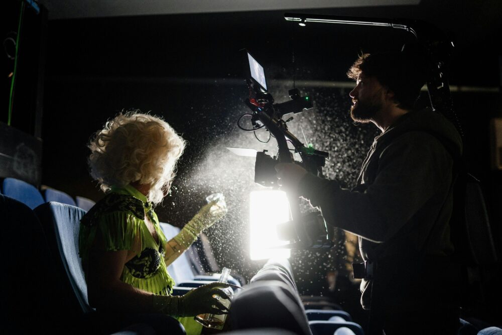 Filmmaker capturing a scene in a dimly lit theater with dramatic lighting effects