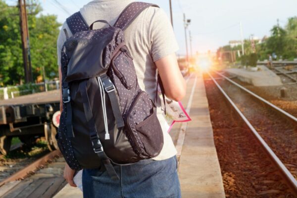A person with a backpack waits at a railway station during daytime