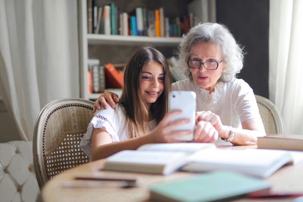 A grandmother and granddaughter bonding over a smartphone at home, showcasing generational connection