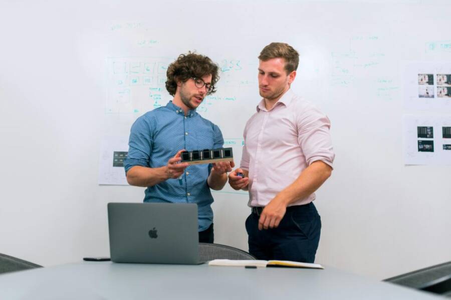 Two men in an office discussing and reviewing a tech prototype