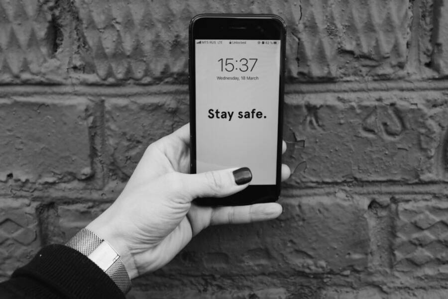 image showing a person holding a smartphone with a caution message