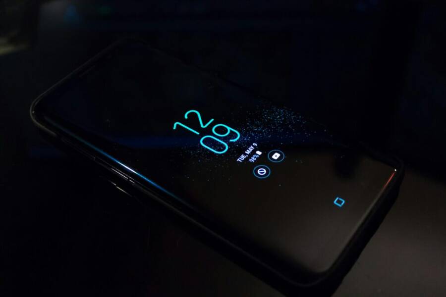 Close-up of a smartphone in the dark displaying digital clock and notifications