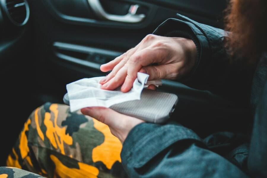 photo of a person sanitizing a smartphone inside a car