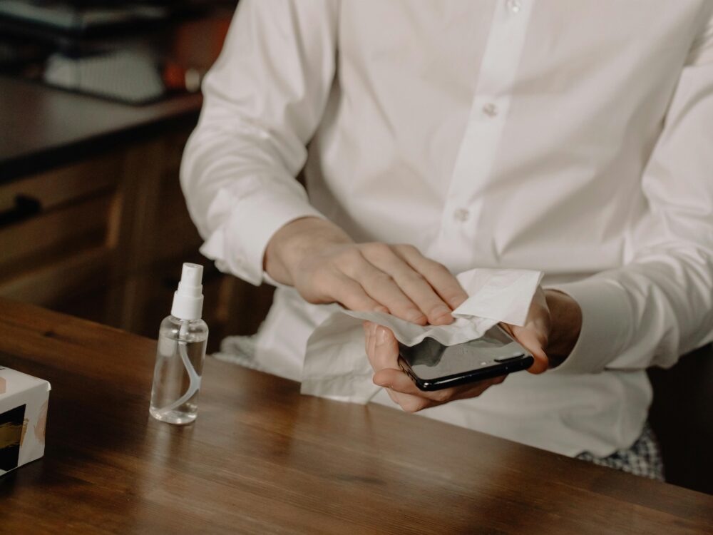 A person sanitizes their smartphone at a table, promoting healthy hygiene in home settings