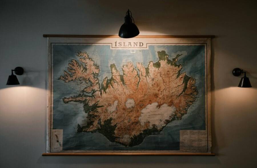 A vintage map of Iceland illuminated by warm lights on a museum wall