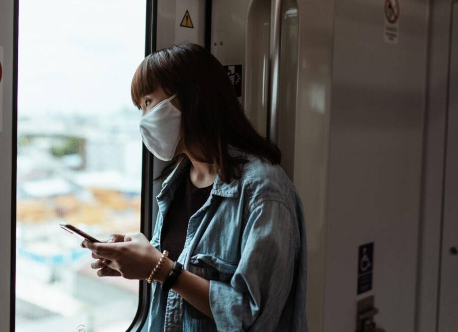 亞洲女性在列車上使用智慧型裝置，窗外風景模糊