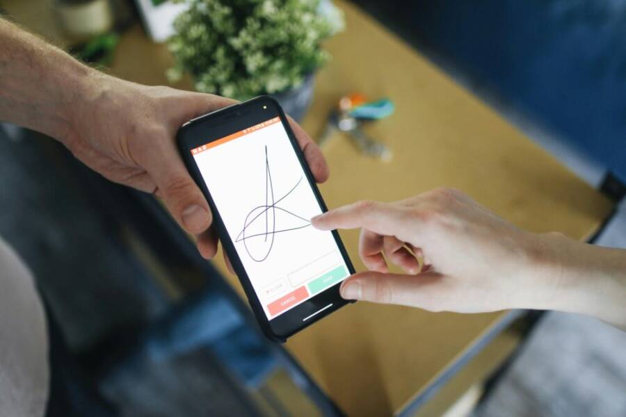 Two people completing a digital transaction with electronic signature on a smartphone screen