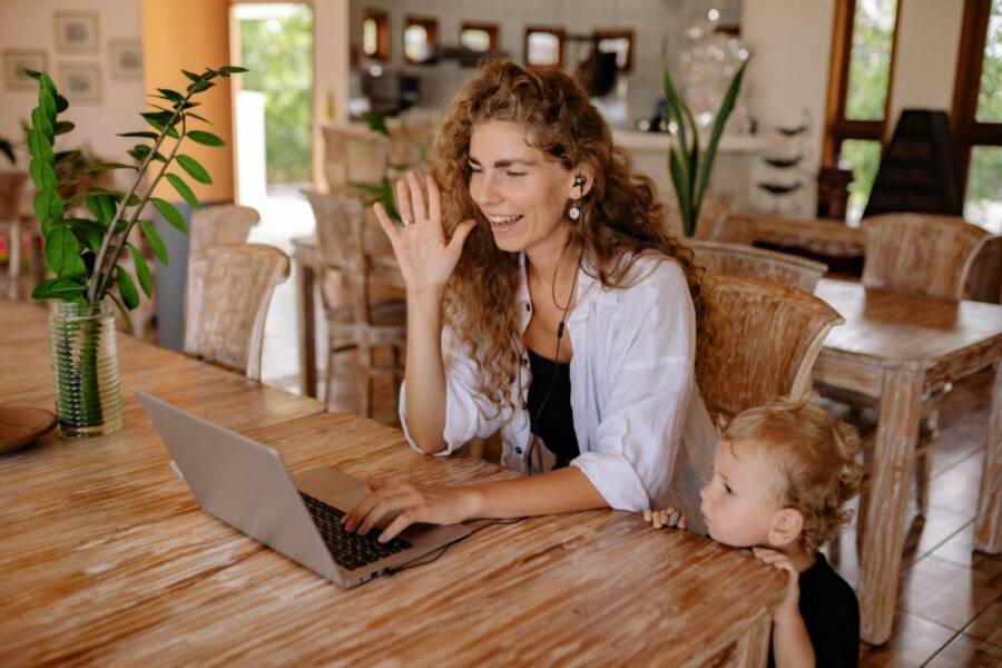 A mother and child enjoy a video call together at a cozy wooden table.