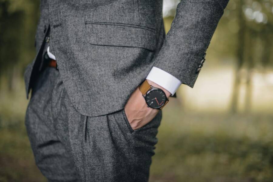 Close-up of a man in a tailored suit wearing an elegant wristwatch outdoors