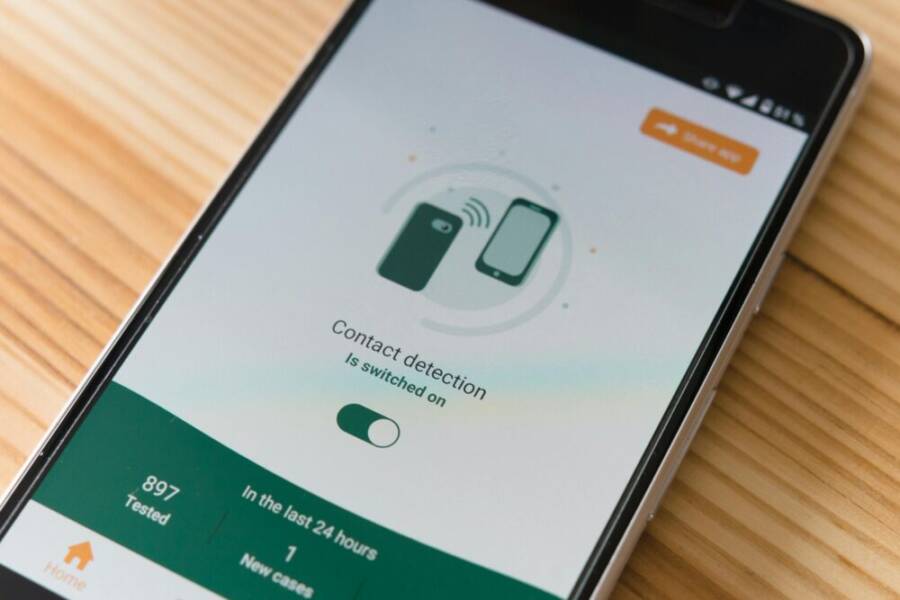 Close-up of smartphone displaying contact detection app on wooden surface