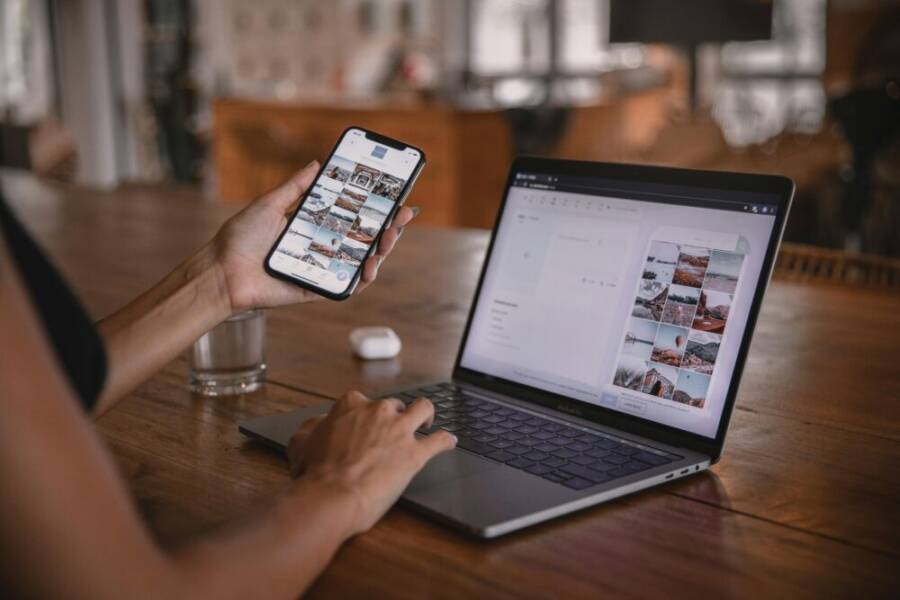 image of a person editing social media content on a phone and laptop at a cafe