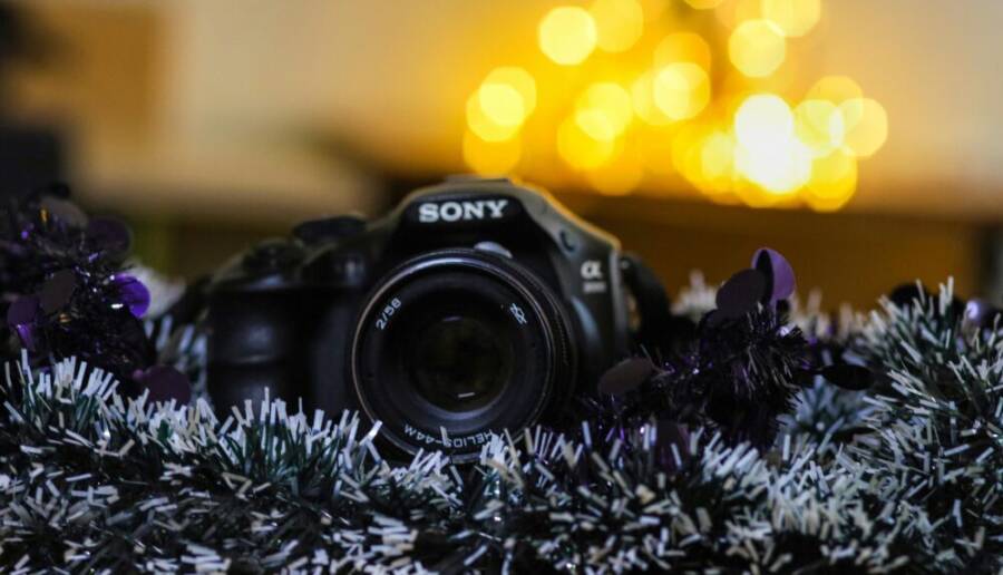 A camera surrounded by colorful tinsel and bright bokeh lights, creating a festive atmosphere.