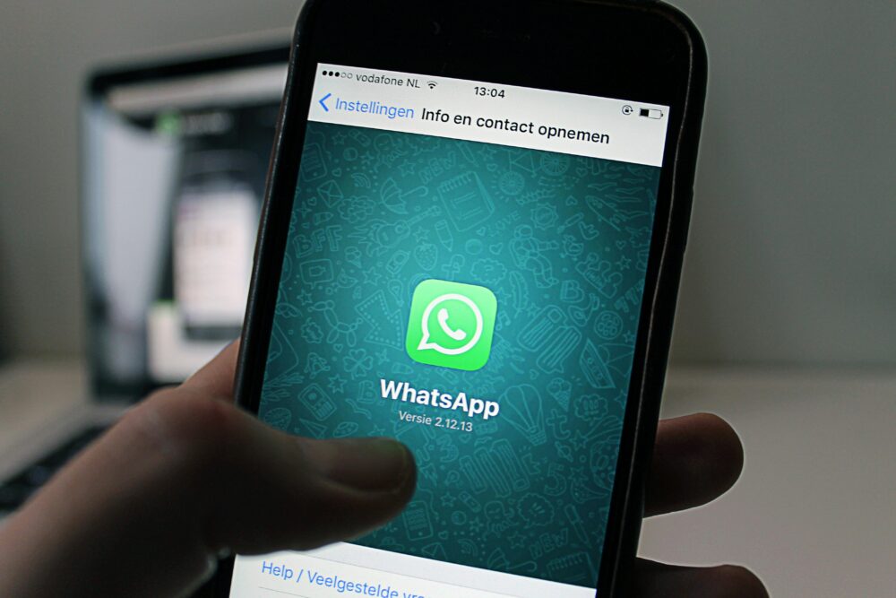 A smartphone displaying the WhatsApp application screen held by a person