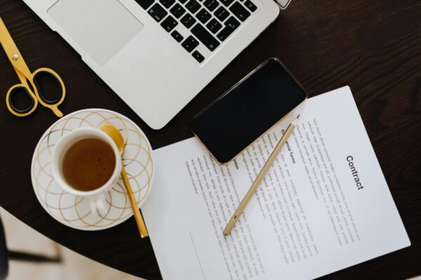 Top-view of a workspace with contract, coffee, laptop, and smartphone focused on business productivity.