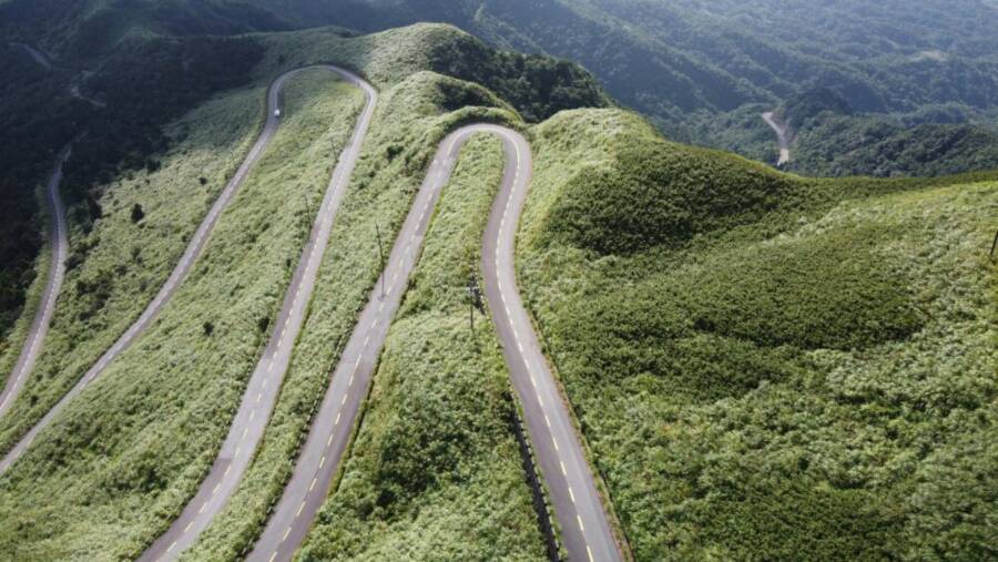 Aerial view of winding mountain road amidst lush greenery in Ruifang, Taiwan
