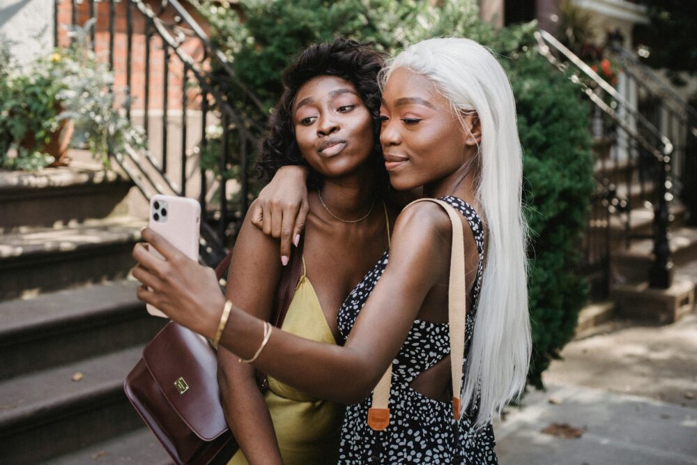 Two women joyfully taking a selfie together on a sunny day, capturing the moment.