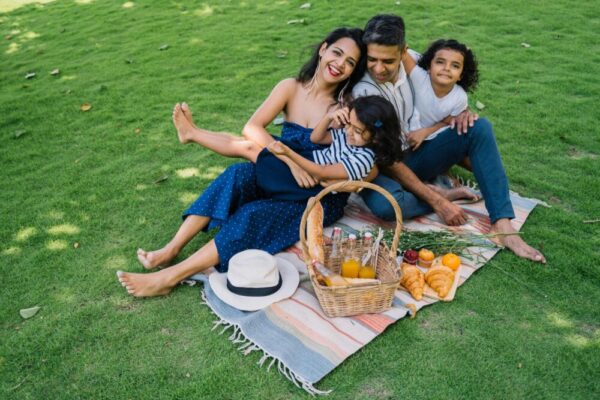Cheerful family enjoying a picnic on a lush green lawn with food basket and smiles.