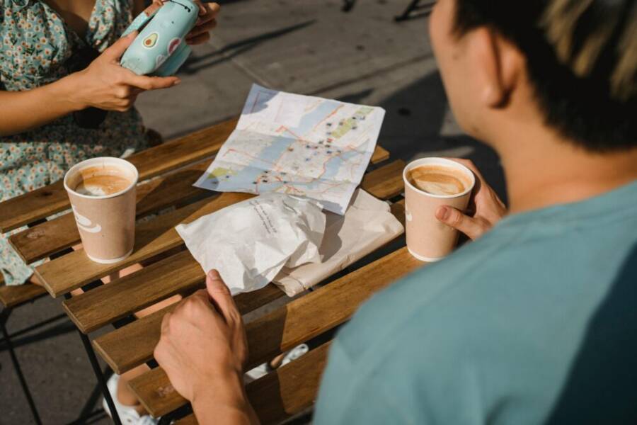 A couple with coffee and a map planning their travel adventure at an outdoor cafe