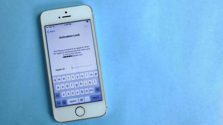 Top view of a smartphone showing activation lock screen on light blue surface