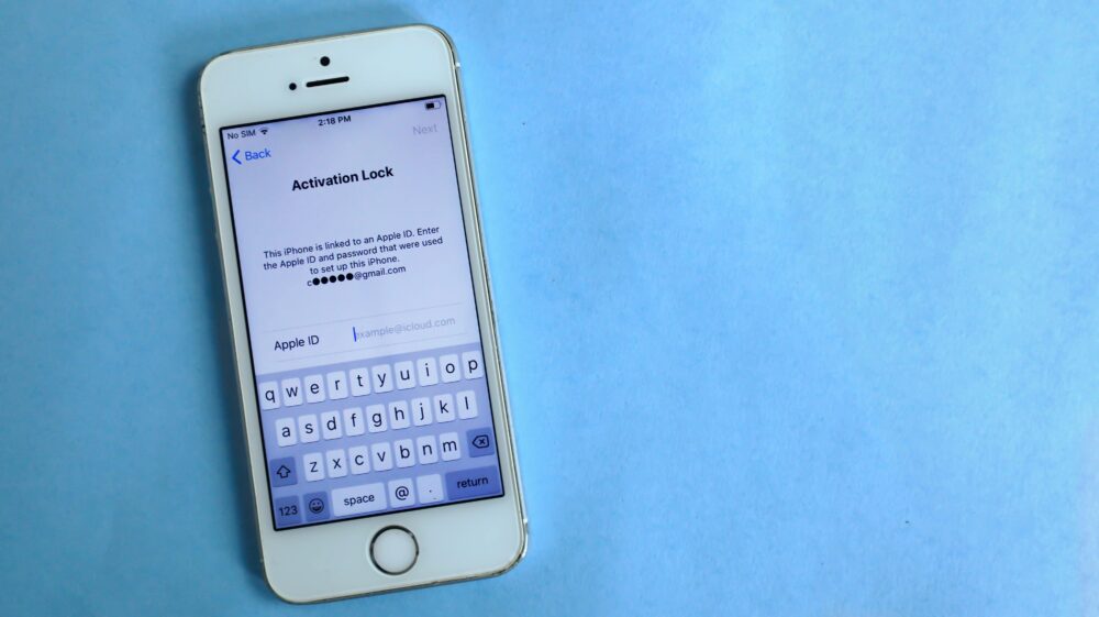 Top view of a smartphone showing activation lock screen on light blue surface.