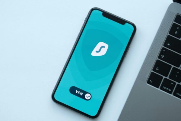 Flat lay of a smartphone showing a VPN app next to a laptop on a desk