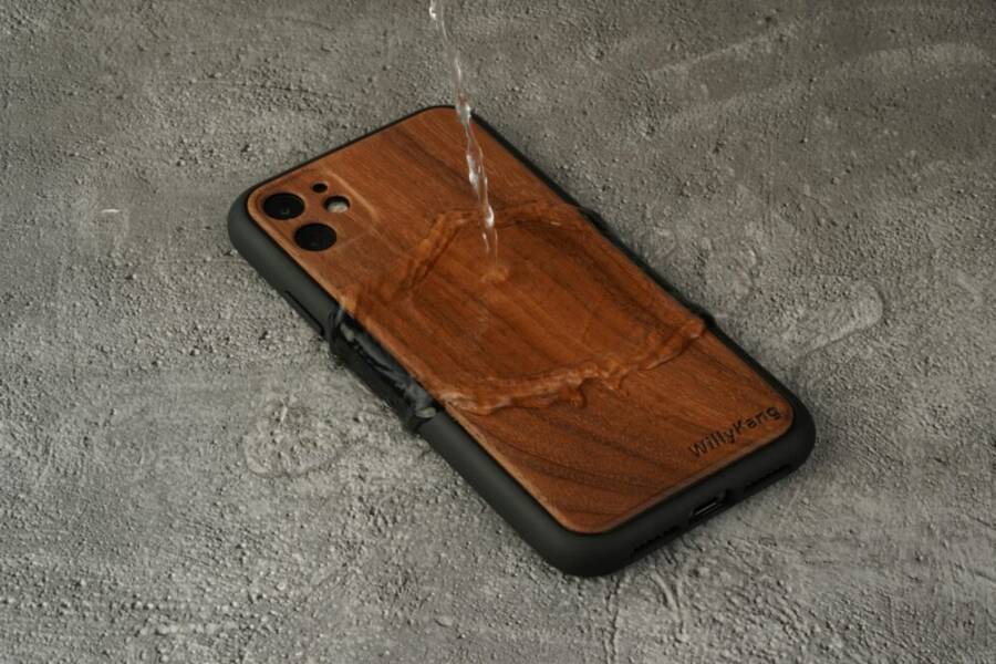 Durable waterproof wooden phone case with water pouring on a concrete background.