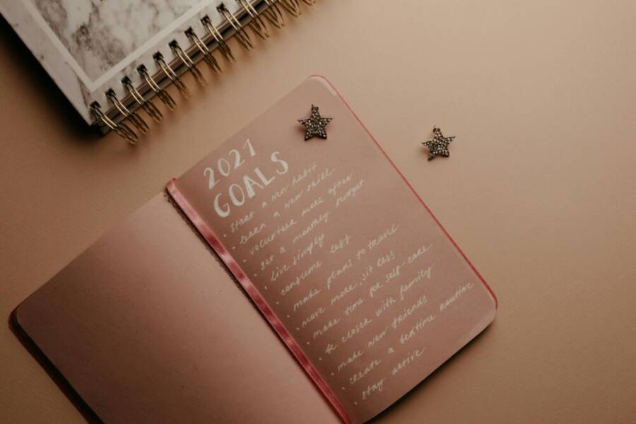 Top view of a 2021 goals notebook with handwritten list and star decorations, ideal for planning inspiration
