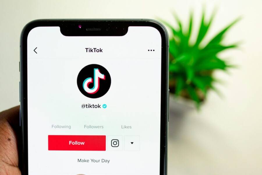 Close-up view of hand holding smartphone displaying TikTok app interface with profile page.