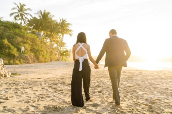 A couple walking along a sandy beach at golden sunset