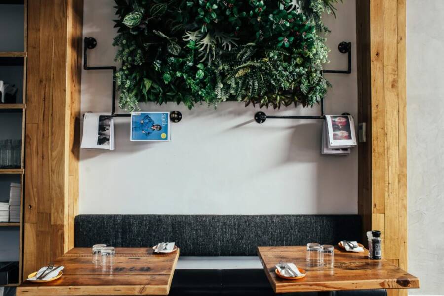 Contemporary cafe interior featuring a wooden table, bench seating, and a lush vertical garden.