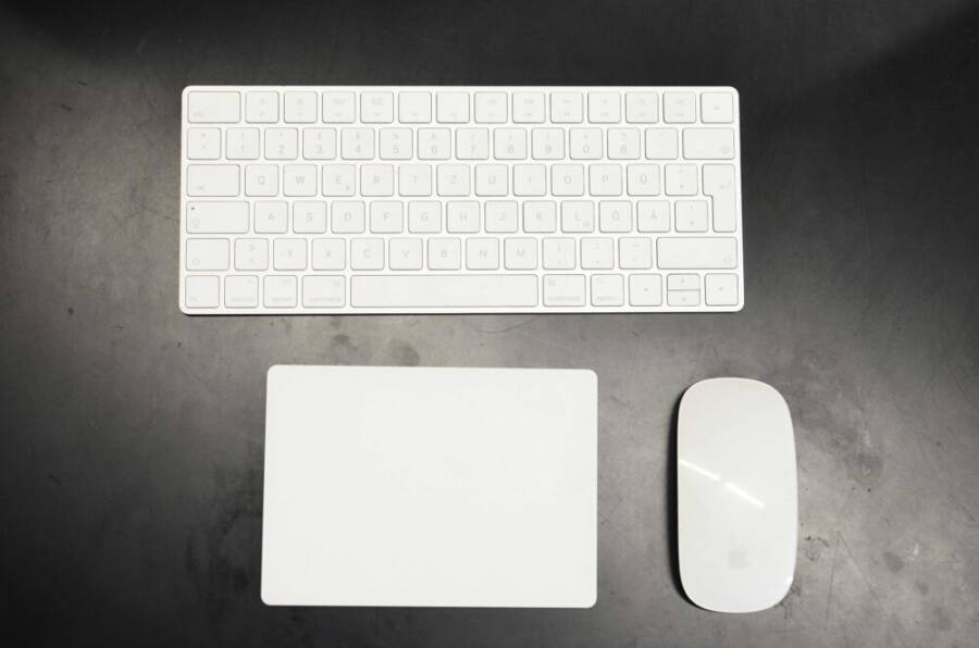 Top view of modern wireless white keyboard and mouse with pad placed on black table