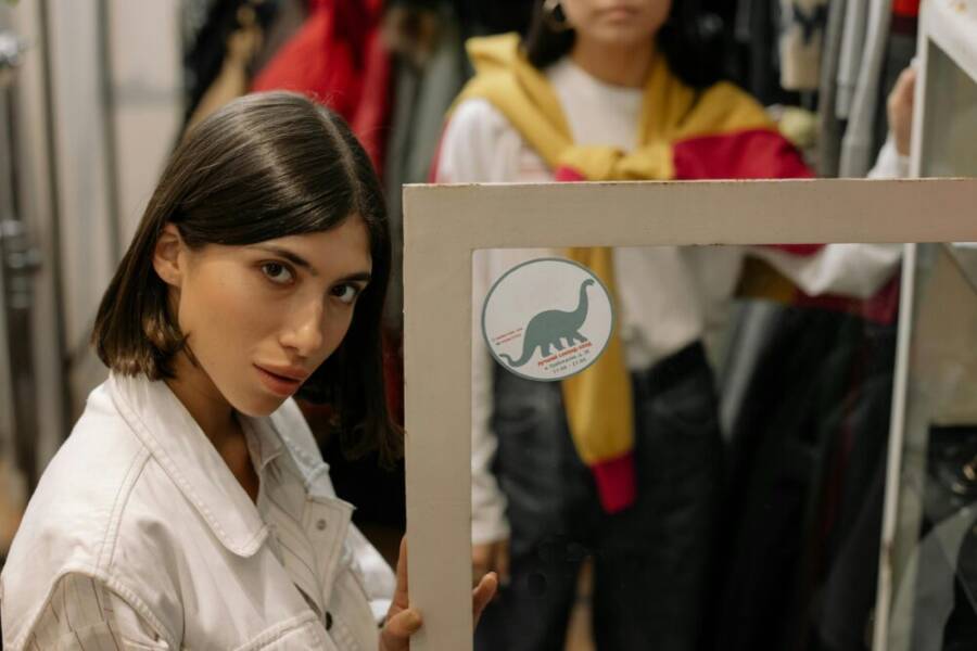 Young woman in a fashionable boutique posing confidently in front of a mirror